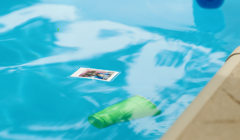 A card and a cup floating in a pool