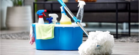 A blue bucket filled with cleaning supplies on grey, sparkling floor