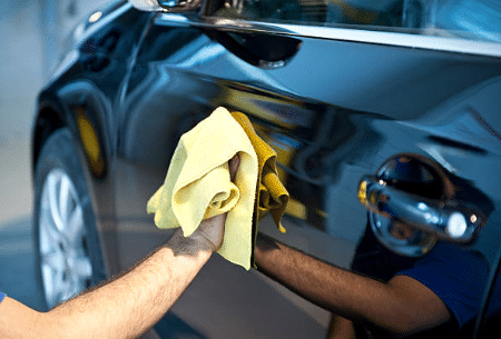 A man wiping his car with a towel